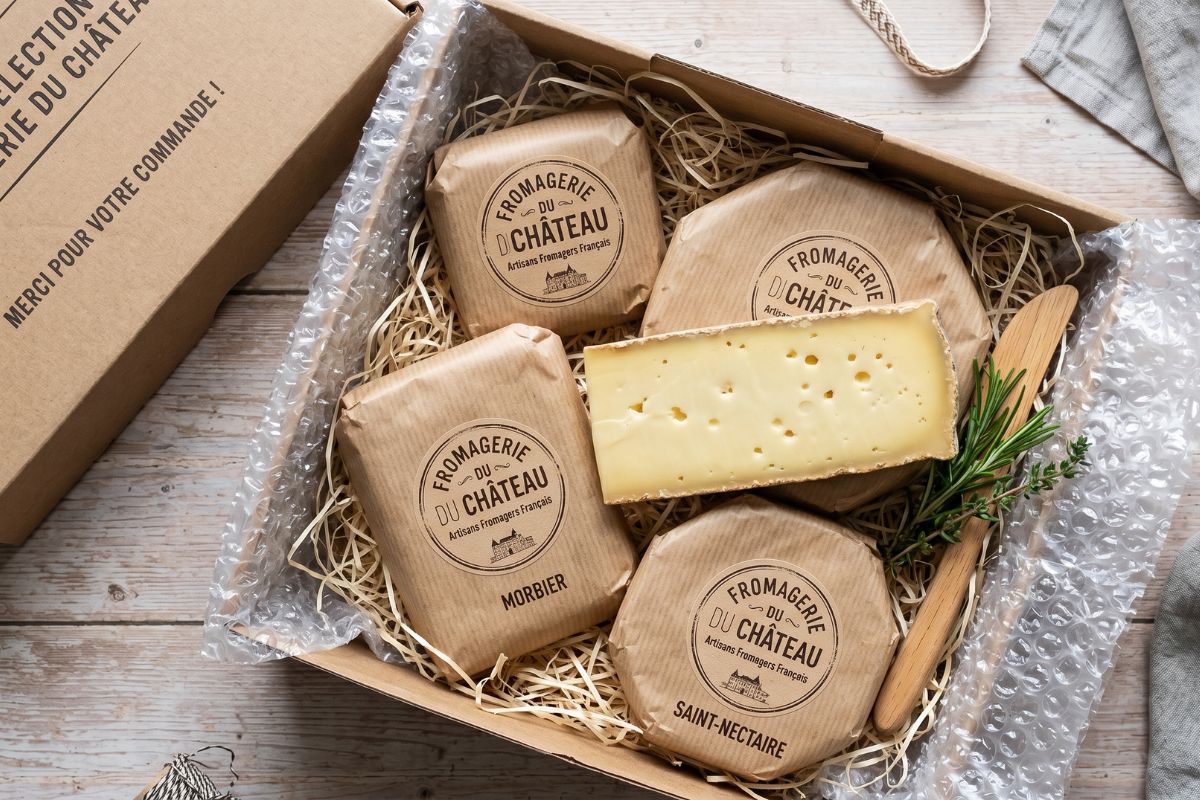 Boîte de livraison de fromages artisanaux ouverte avec fromages emballés sous vide