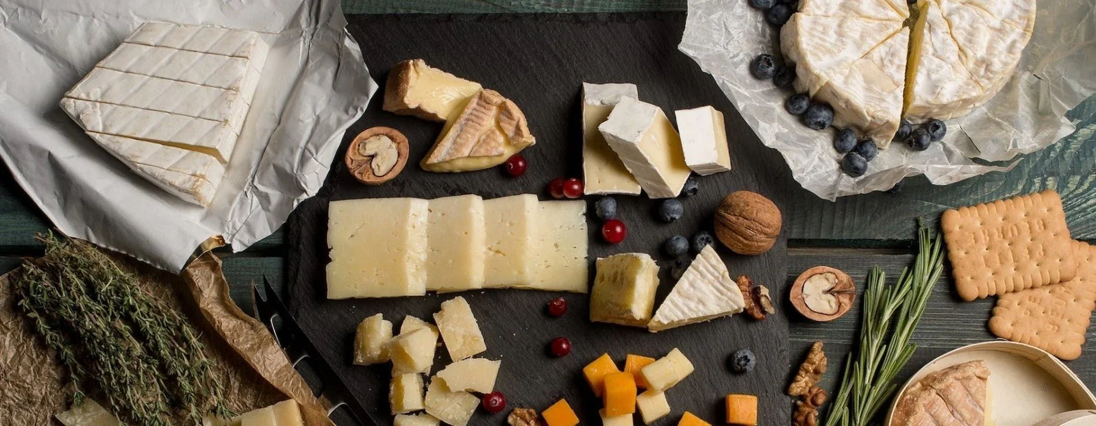 Plateau de fromages artisanaux variés avec fruits secs, baies et biscuits sur table en bois